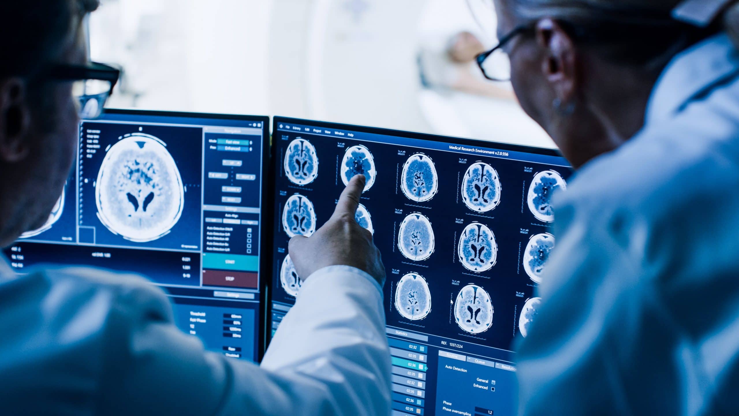 Doctors pointing at a screen with images of the brain