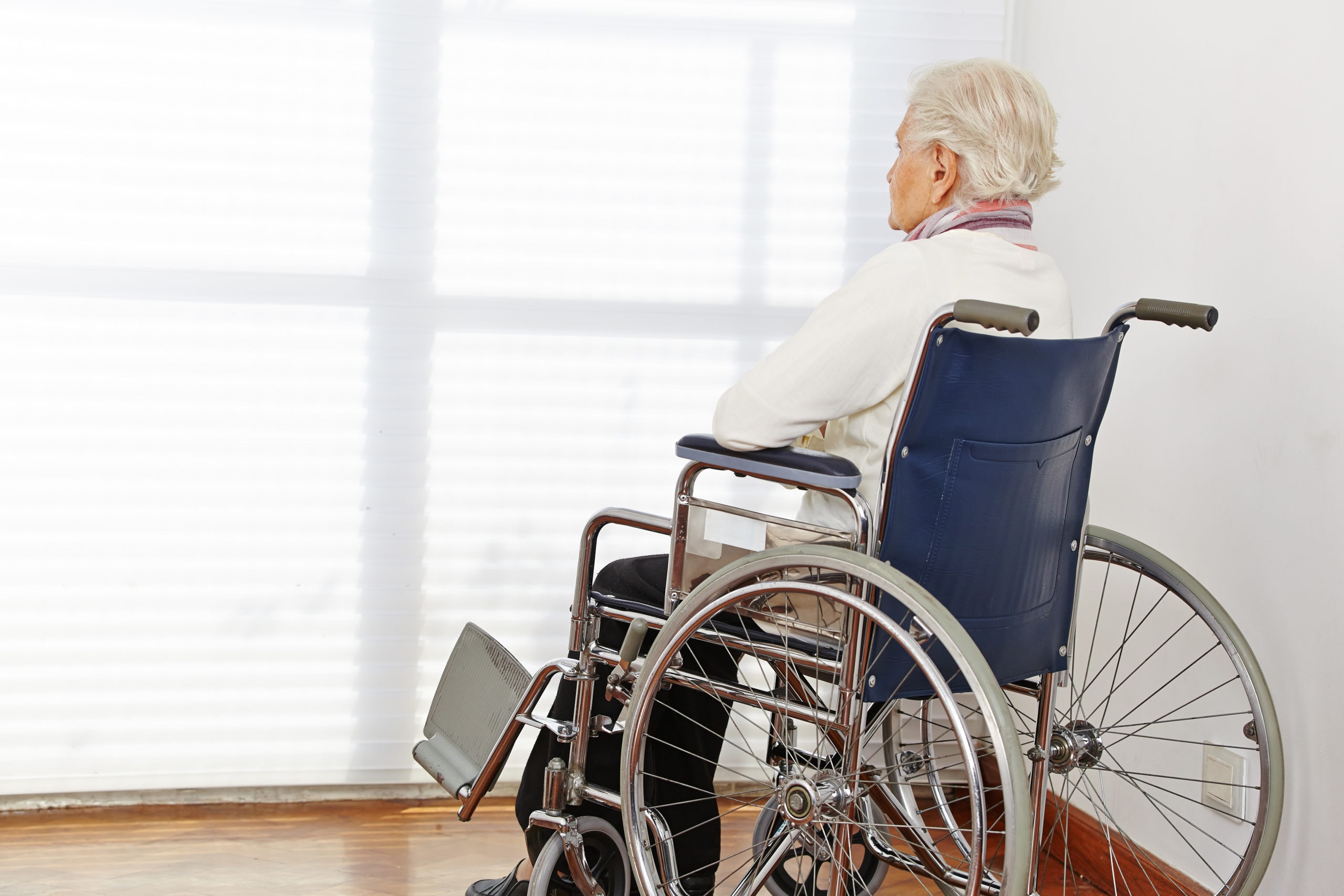 Elderly lady sitting in wheelchair looking at window