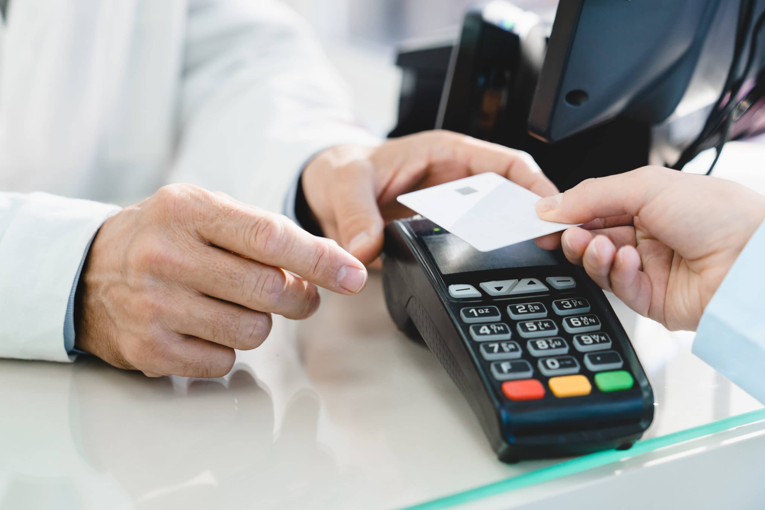 Person holding credit card over card scanner attempting to purchase an item