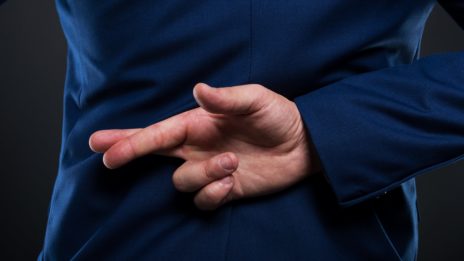 business man with fingers crossed behind back