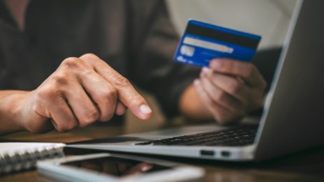 person typing on laptop and using credit card to shop online