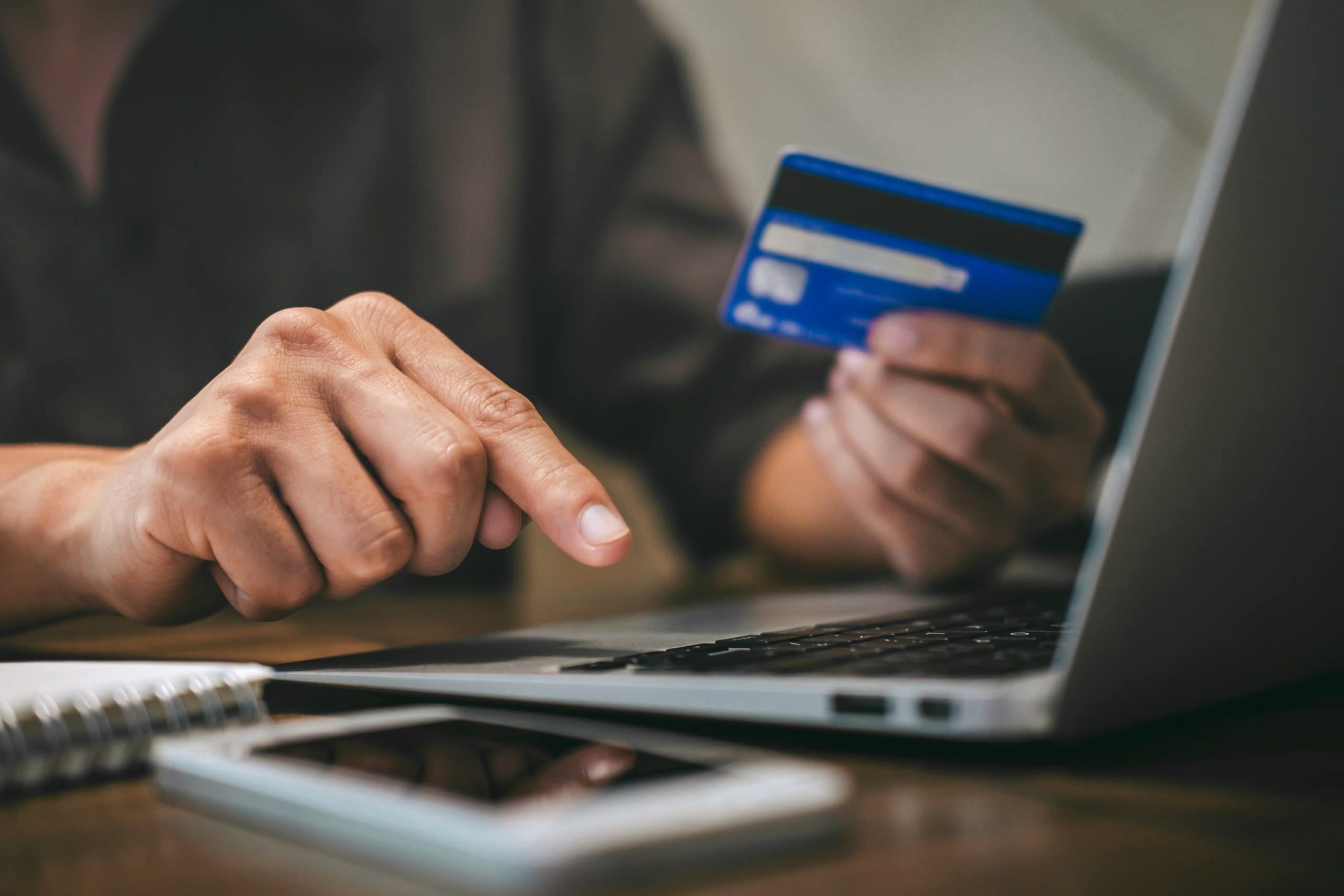 person typing on laptop and using credit card to shop online