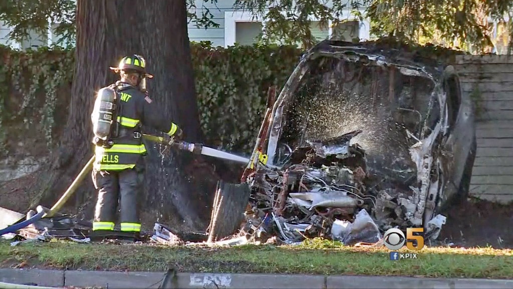 Fireman putting out smoldering crashed Tesla Model X