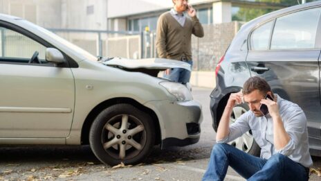 two men using cell phones after a car accident