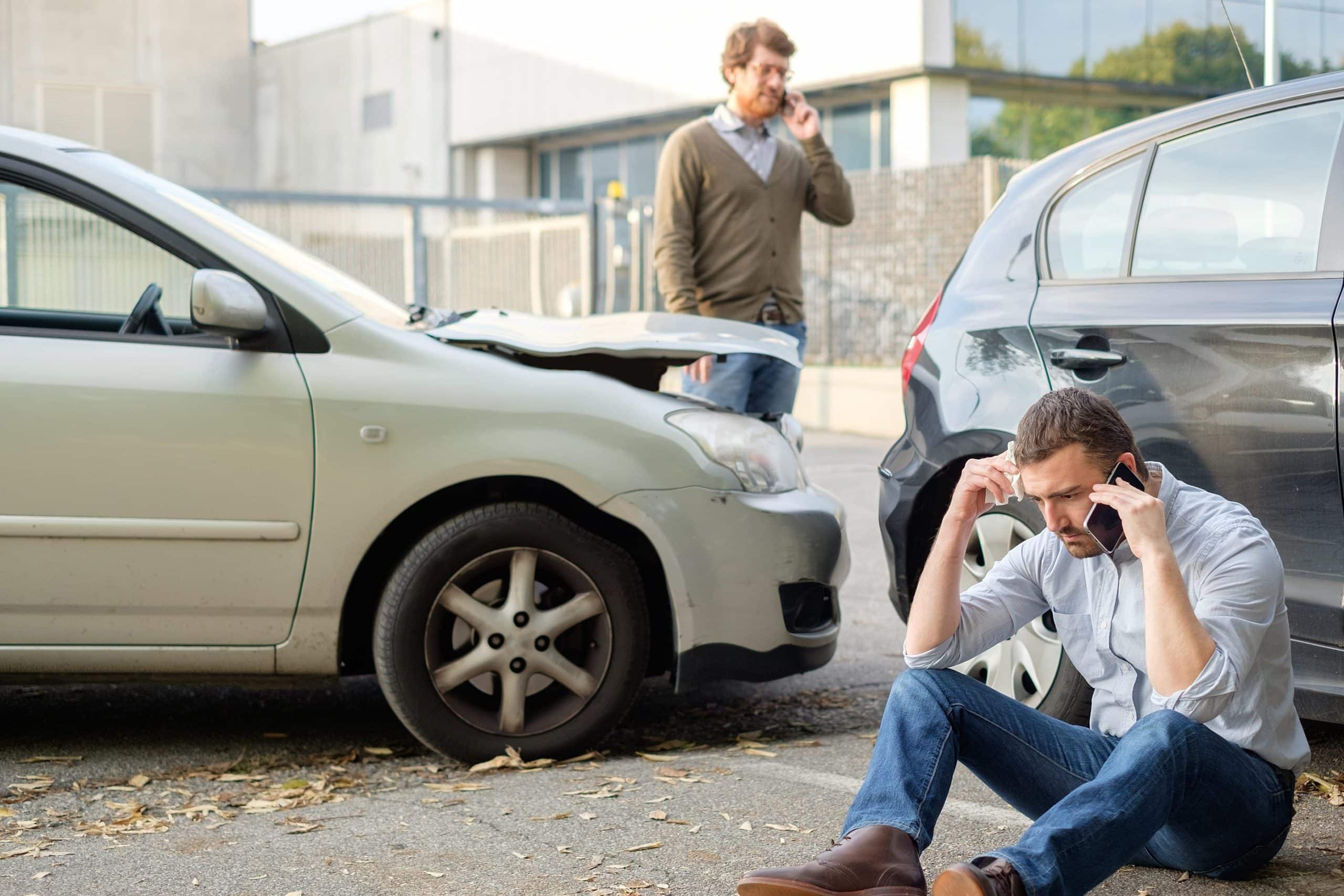 two men using cell phones after a car accident